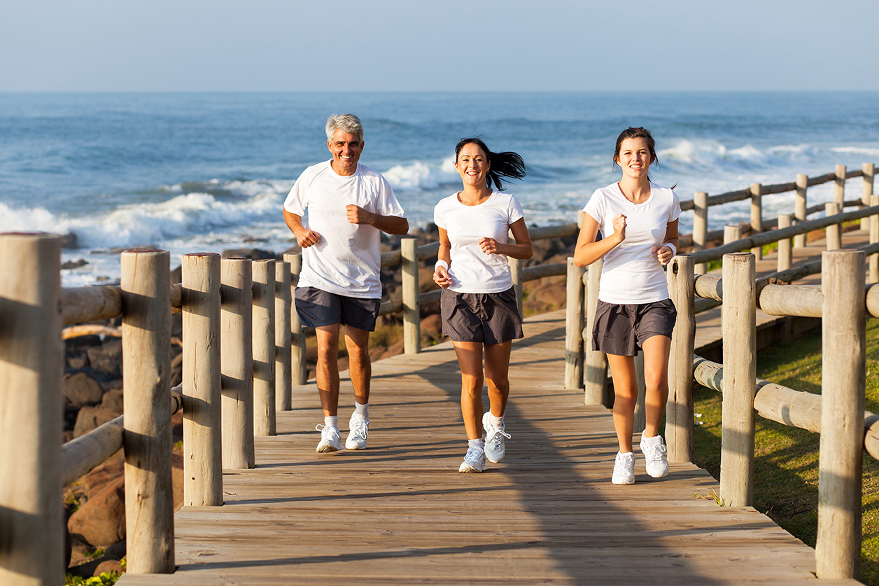 cheerful fit family jogging at the beach in the morning